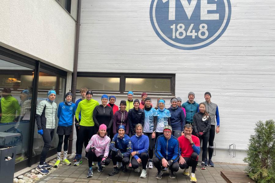 Gruppenfoto von Athleten vor dem Vereinsgebäude mit TVE 1848-Logo