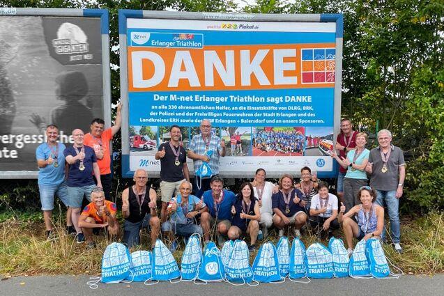 Gruppenfoto von Helfern vor einem Erlanger-Triathlon-Danke-Poster