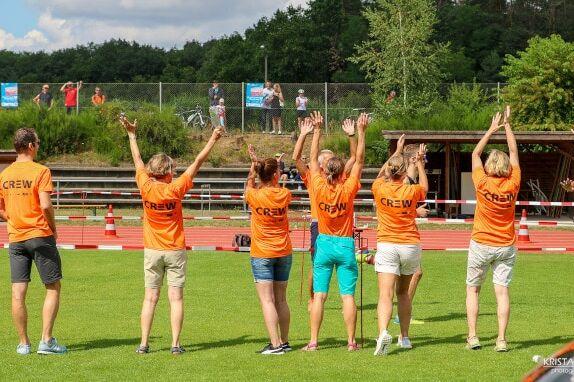 Foto einer Helfergruppe mit erhobenen Armen in orangenen Crew-Helfershirts