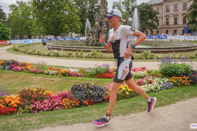 Foto eines laufenden Athleten vor dem Brunnen im Erlanger Schlossgarten
