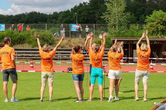 Foto einer Helfergruppe mit erhobenen Armen in orangenen Crew-Helfershirts