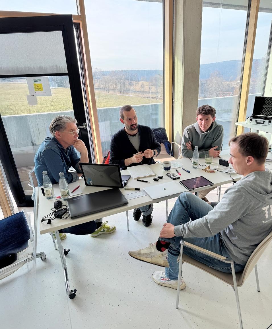 Sportklausur 2025 Vier Männer sitzen um einen Tisch und reden miteinander.