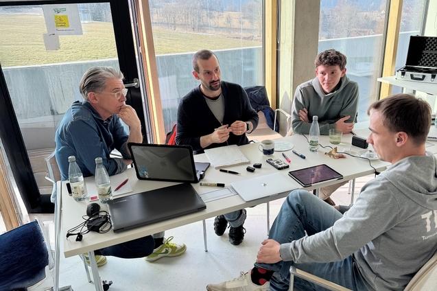 Vier Männer sitzen um einen Tisch und reden miteinander.