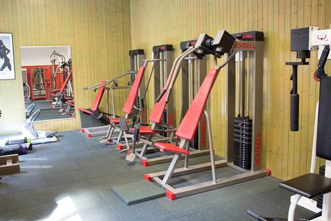 Blick auf Fitnessger&auml;te im Kraftraum der Jahnhalle, die an der Wand entlang aufgestellt sind, mit einem Spiegel im Hintergrund.