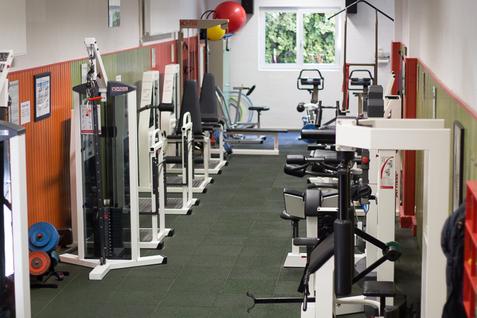 Blick auf die gesamte Ausstattung des Kraftraums in der Jahnhalle, mit verschiedenen Trainingsgeräten entlang der Wände.