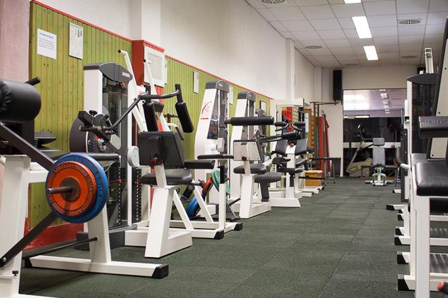 Mehrere Trainingsgeräte in einer Reihe im Kraftraum der Jahnhalle.