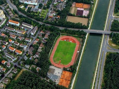 Sportgelände am Kosbacher Weg aus der Luft Luftaufnahme des Sportgeländes am Kosbacher Weg mit einer Laufbahn, einem großen Spielfeld und mehreren Tennisplätzen.