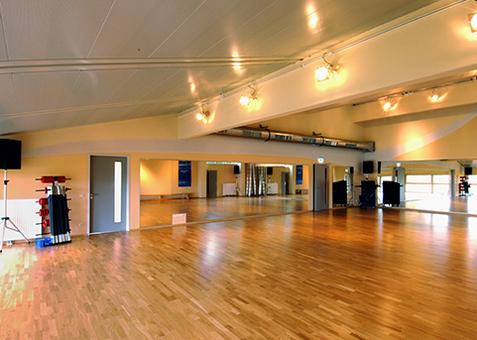 Großer Kursraum im TV Vital mit Holzboden, Spiegelwand und heller Beleuchtung.