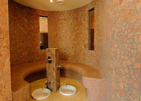 Runder Sitzbereich aus Naturstein mit integrierten Fußbecken in der Wellnesslandschaft des TV Vital.