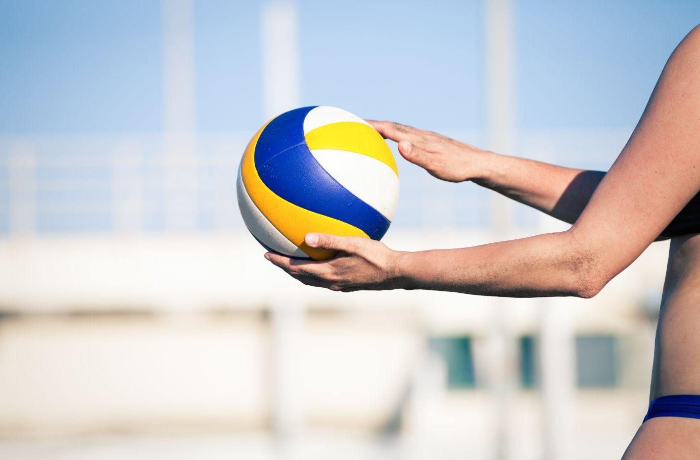 Beachvolleyball-Spieler in Aktion Eine Person hält einen Beachvolleyball in den Händen, bereit zum Aufschlag.