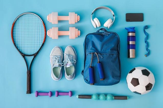Verschiedene Sportutensilien wie ein Tennisracket, Hanteln, ein Rucksack, Schuhe, Kopfhörer und ein Fußball auf einem blauen Hintergrund.