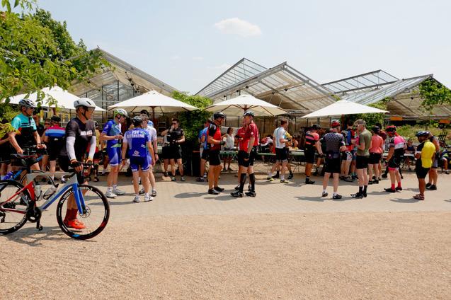 Foto von RTF-Athletinnen und Athleten vor Sonnenschirmen, Tischen und Bänken